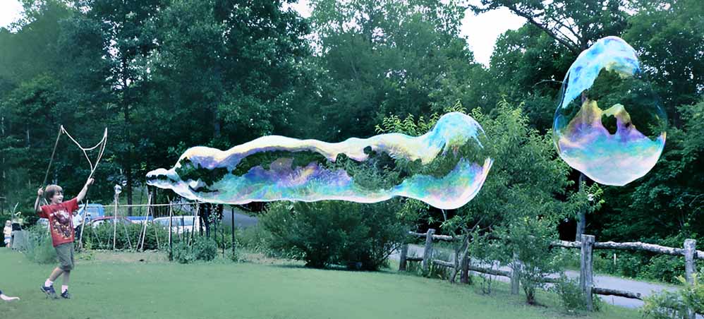 Boy inflating a giant bubble